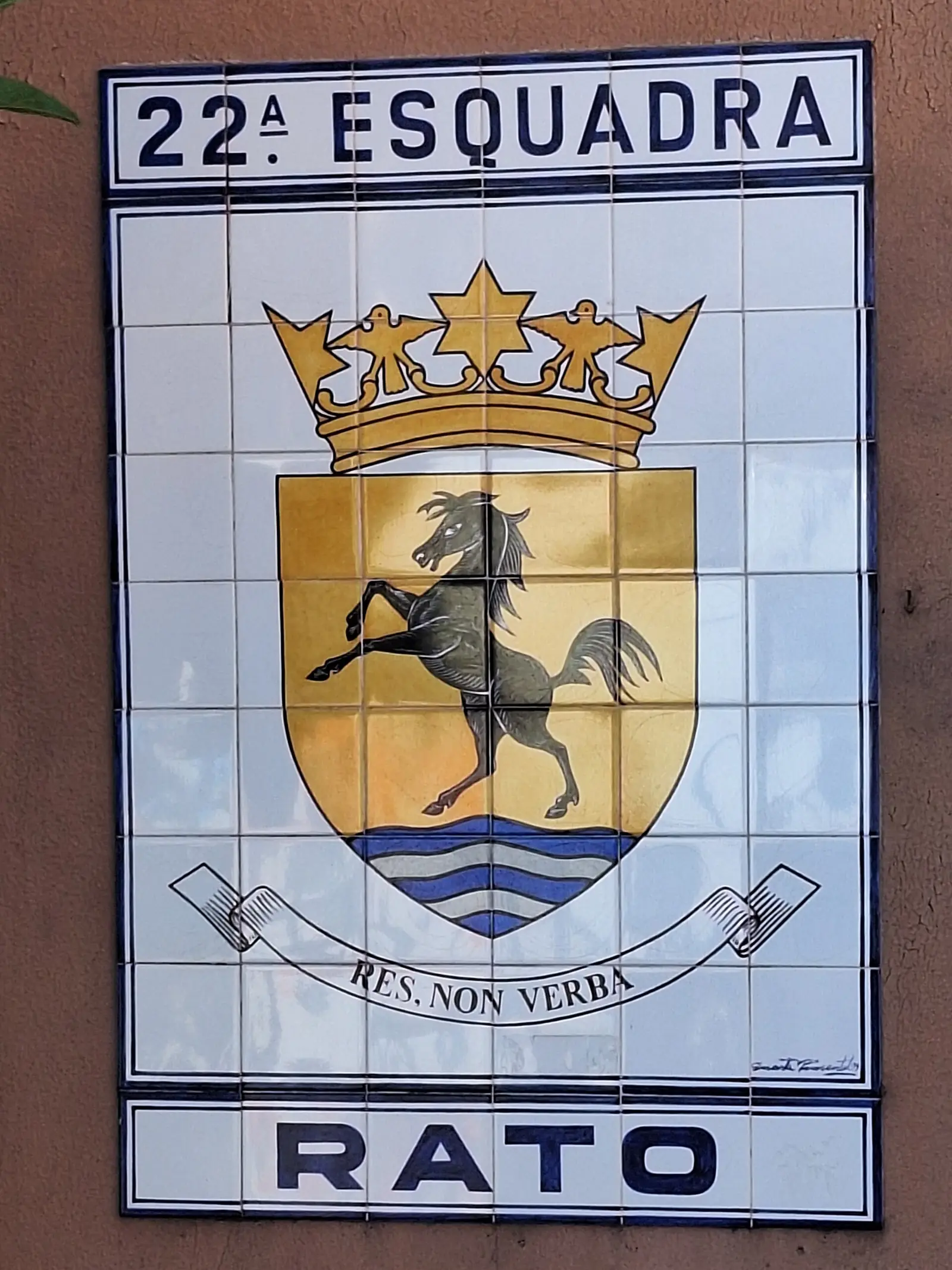 Painel de azulejos com o título «22.ª Esquadra», um escudo dourado com um cavalo negro empinado sob uma coroa, o lema «Res non verba» e a palavra «Rato» em baixo.
